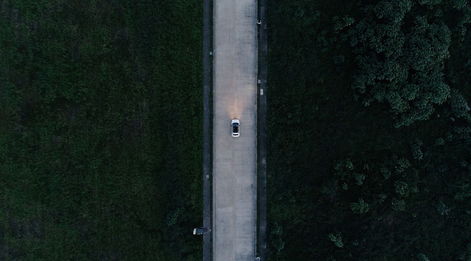 Classic car on a road through the jungle seen from a drone